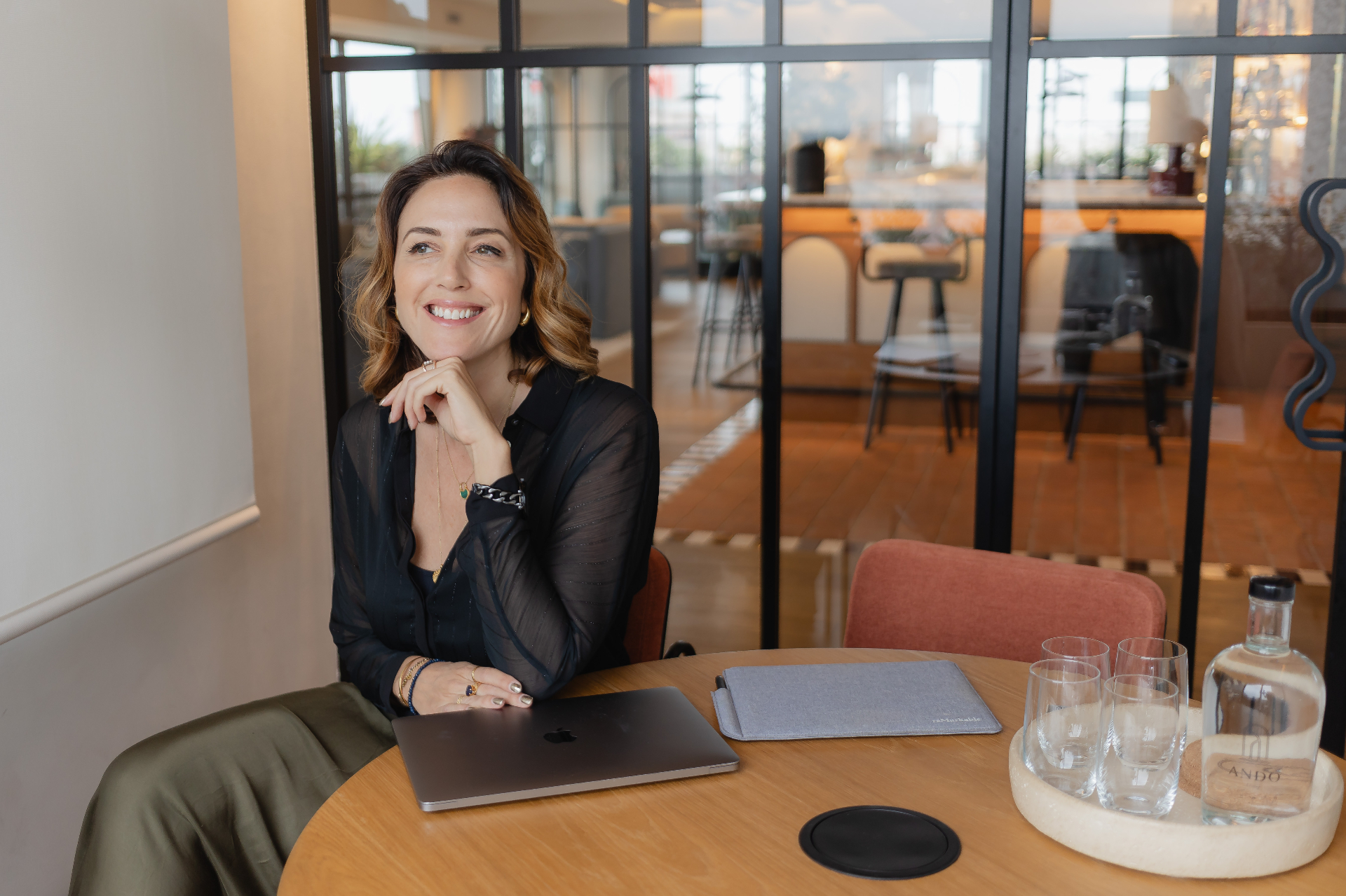 Susanna Kenyon-Muir smiling at a cafe table with her laptop